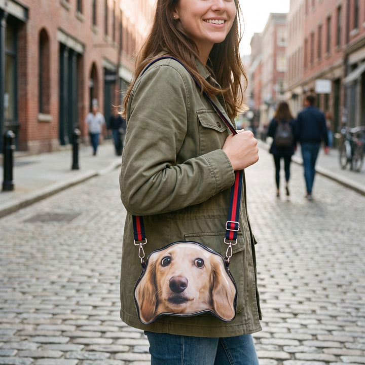 A crossbody bag cut to the shape of a dachshund's head, worn across the body in the street