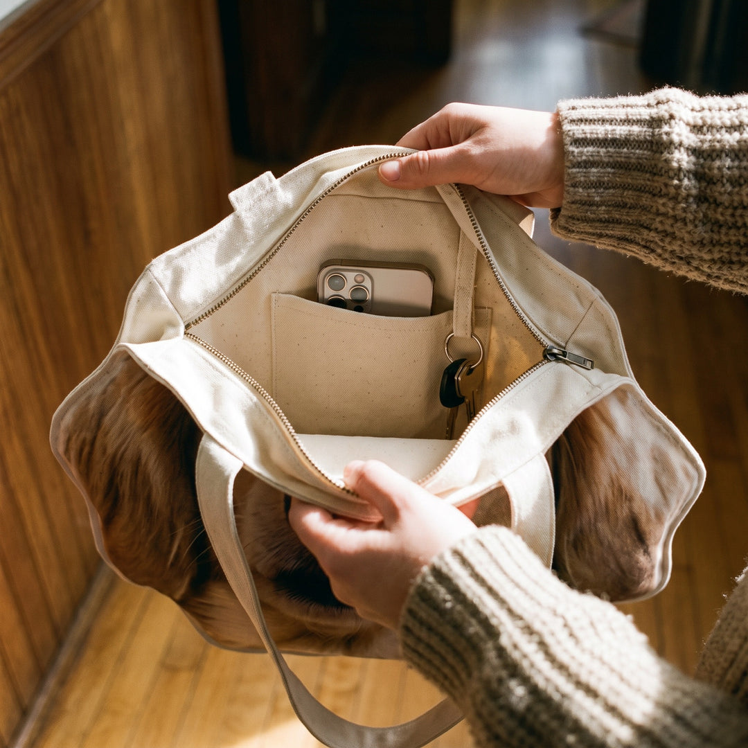 The tote held open, showing the zip and the inner slip pocket with a phone in it