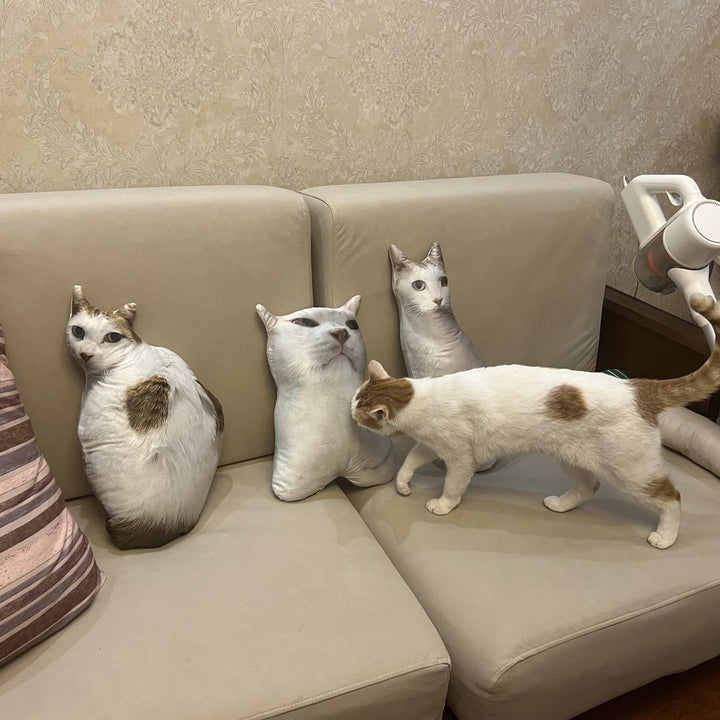 Three cat-shaped pillows standing in a row on a sofa