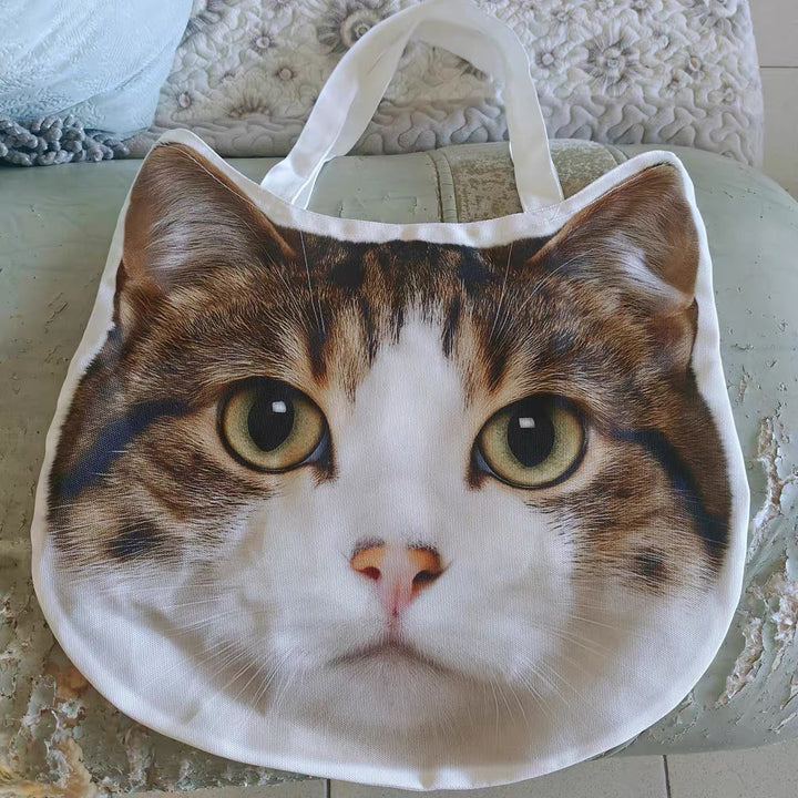 A canvas tote cut to the shape of a cat's face, with webbing handles